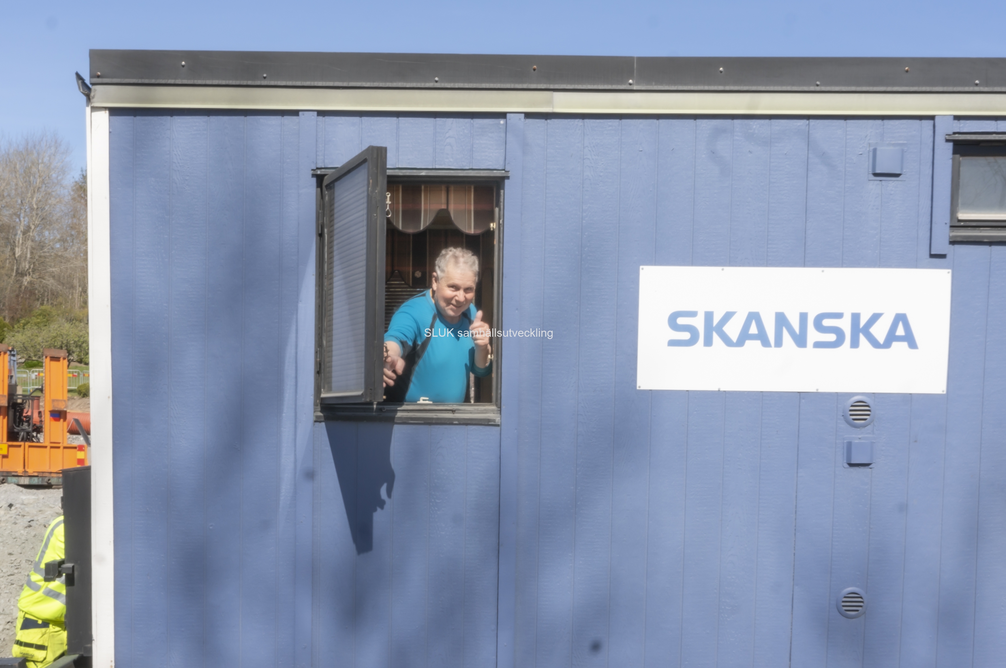 En trevlig man som jobbar för Skanska står i fönstret till arbetsboden.