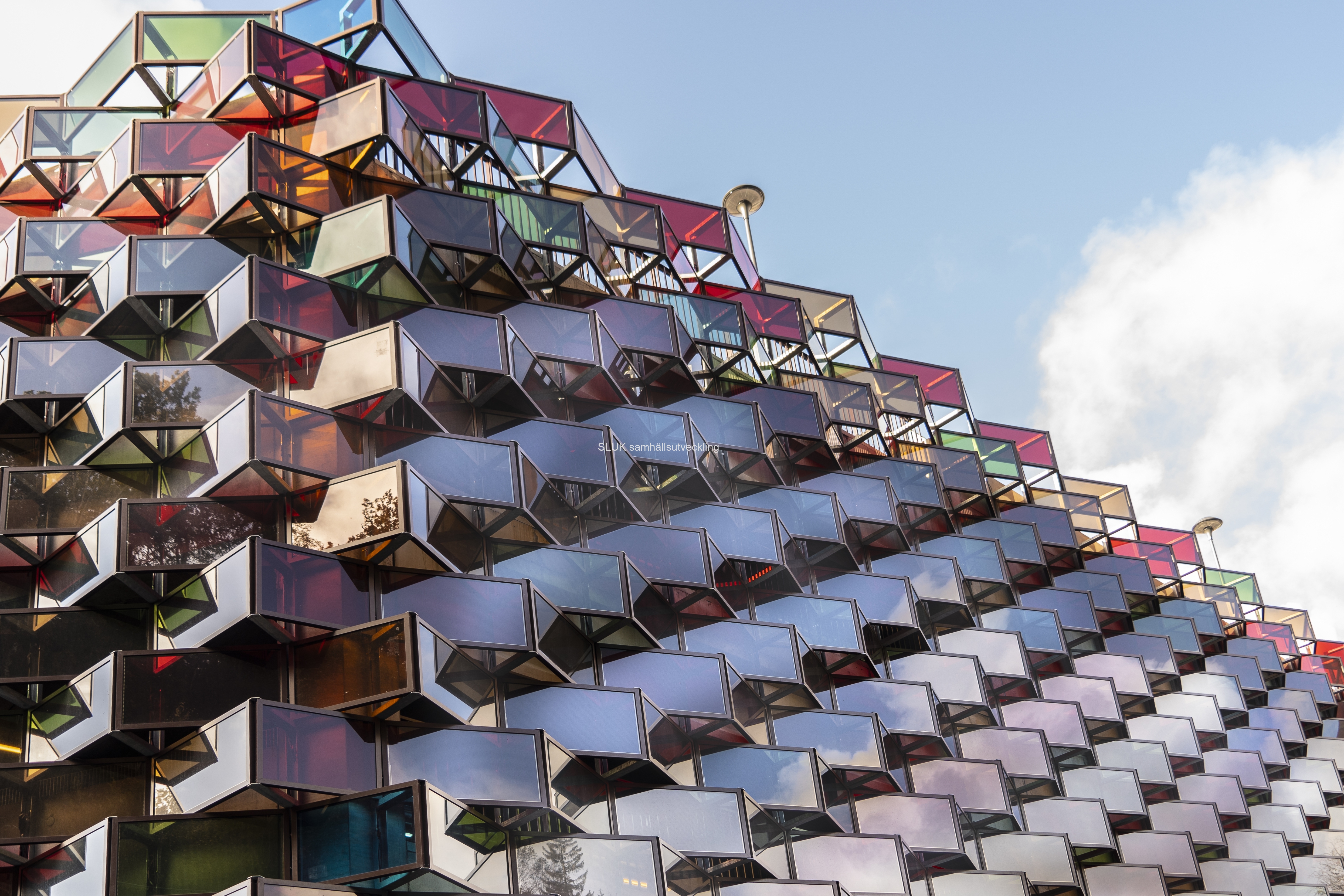 Parkeringshus i Mölnlycke fabriker. fasaden är av glas i olika vinklar och som reflekterar i solljuset.