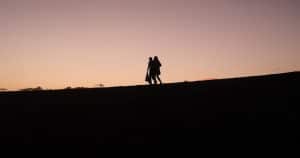 Ett par går ned för en slänt i solnedgång
