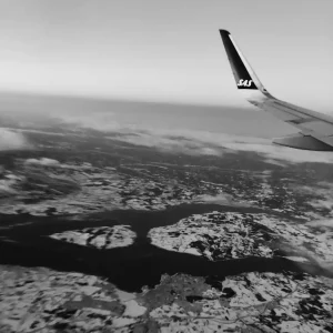 Picture of the wing tip of an airplane flying over Norway in the winter