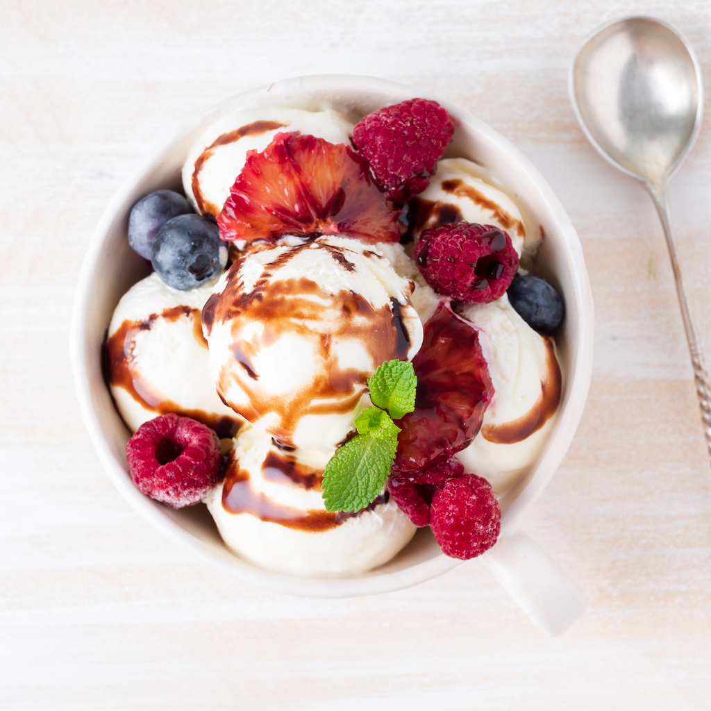 Balls of vanilla ice cream in mug with raspberry and blueberries