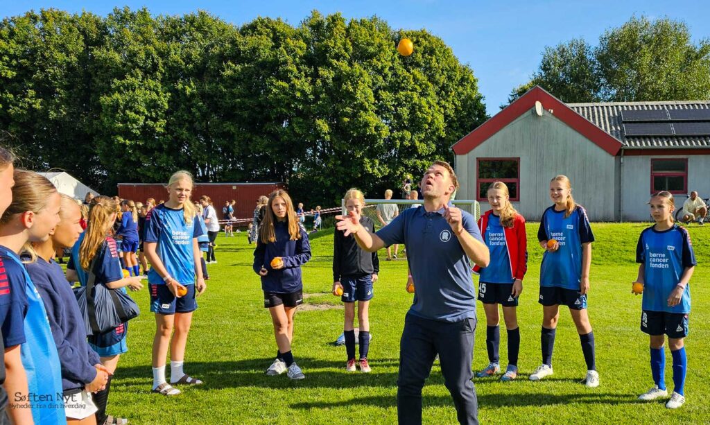 Christian Møller laver mange forskellige tricks med appelsinen, til stor glæde for fodboldskoledeltagerne, inden de selv skal prøve at gøre ham kunsten efter. Foto: Anders Godtfred-Rasmussen - Søften Nyt.