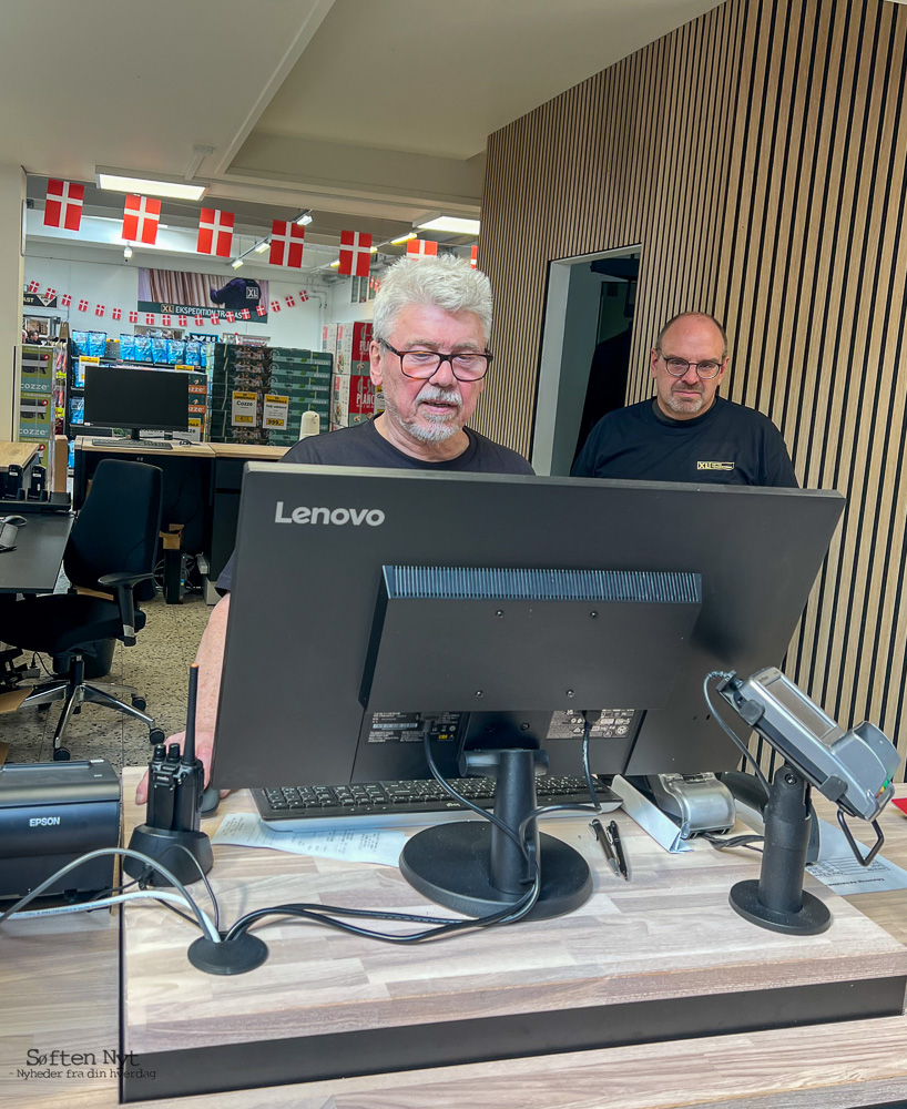Billedet viser en Lenovo skærm, hvor der bagved står to XL-Byg medarbejdere, der er ved at finde ud af, hvordan det nye IT system virker.