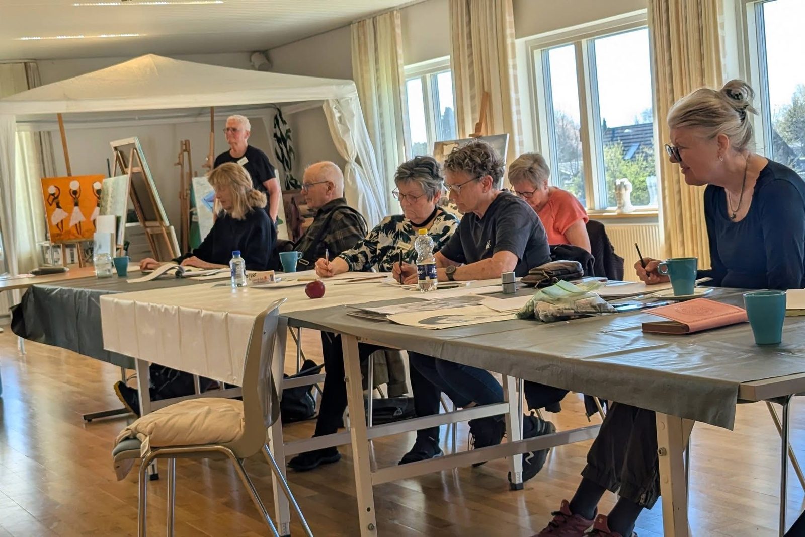 Medlemmer tegner ved de lange borde i malelokalet hos OJD
