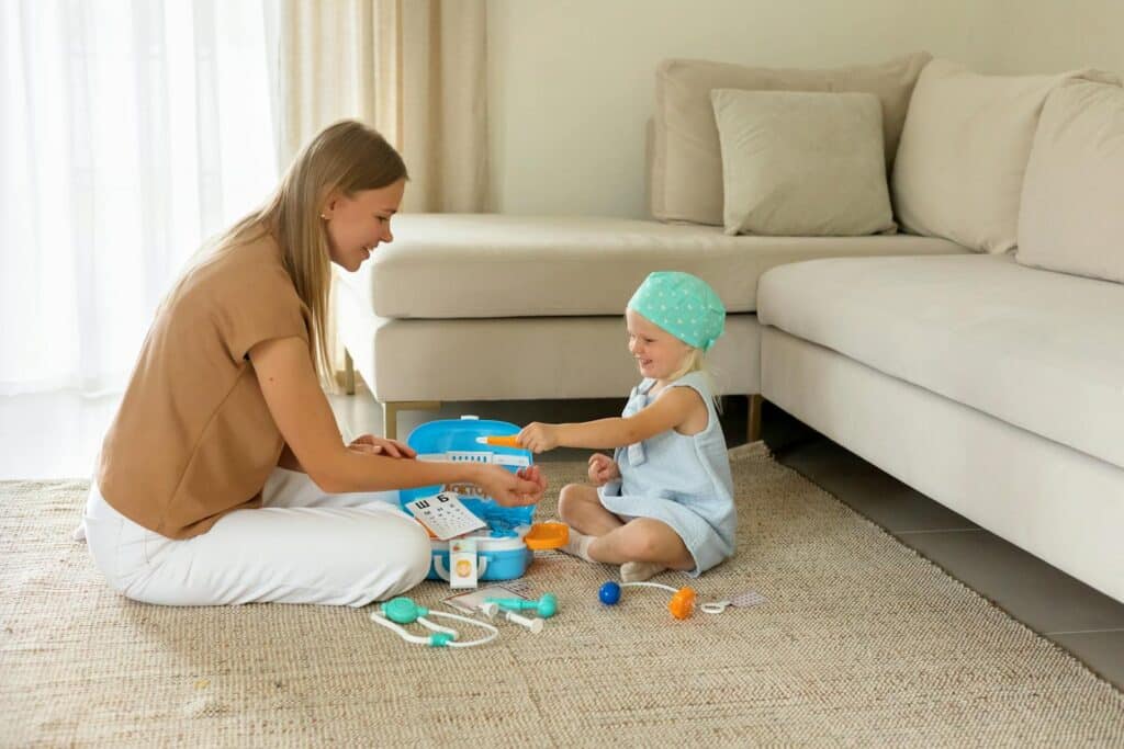 A mother and daughter engage with a toy doctor kit on the living room floor, fostering creativity and learning.