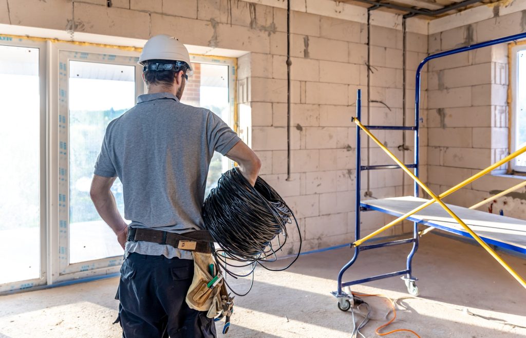 An electrician contractor examines a blueprint at a construction site.