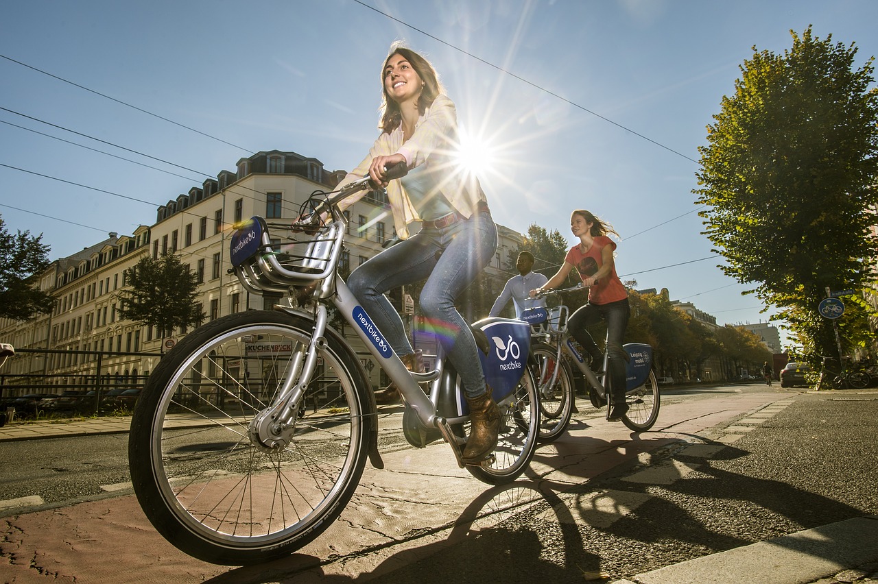 Zwei Frauen auf je einem Fahrrad auf einem rot markieren Radweg in einer Stadt.