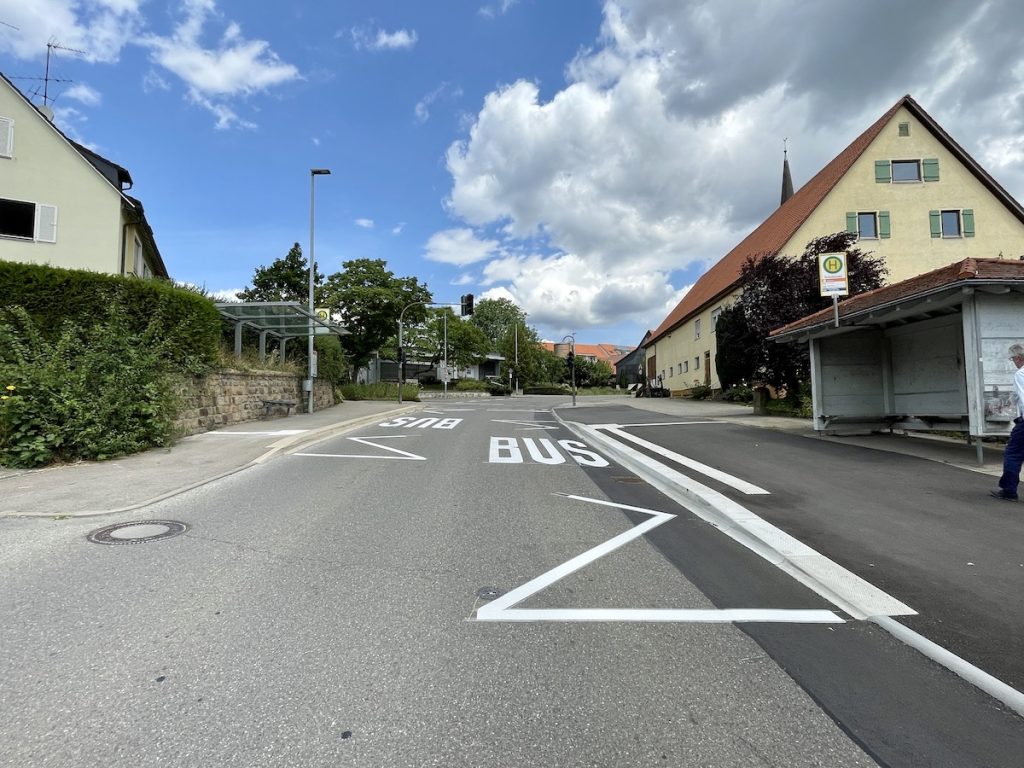 Zwei Bushaltestellen gegenüber, jeweils am Straßenrand mit speziellen Busbordsteinen und Blindenleitstreifen.