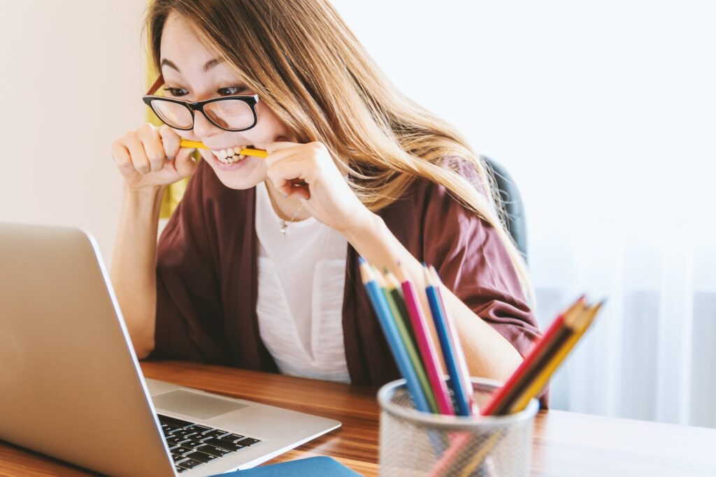 How make money online . woman biting pencil while sitting on chair in front of computer during daytime