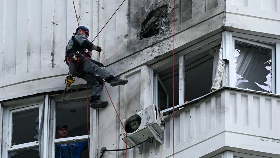 An expert examines the exterior of a residential high-rise building following an alleged drone attack.