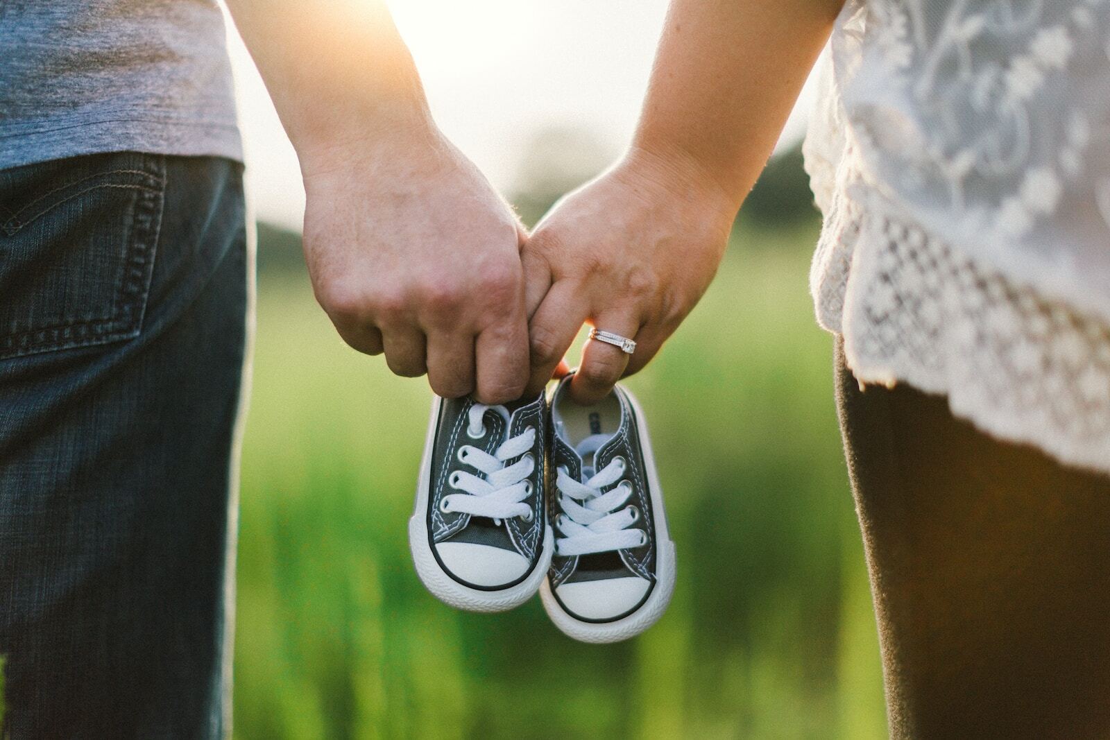 The Global Day of Parents: Celebrating the Vital Role of Parents in Shaping the Future of Society woman and man holding black crib shoes standing near green grass during daytime