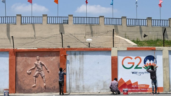 Artists add finishing details to a street wall mural in preparation for the upcoming G20 meeting in Srinagar on May 19, 2023.