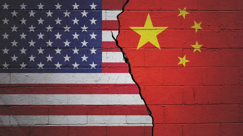China's and America's flags painted symbolically on a brick wall representing the divide.