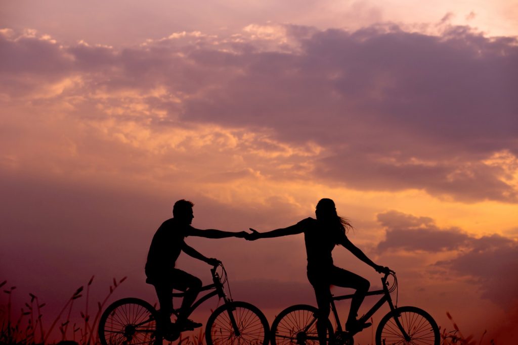 How to Improve Communication in Your Relationship woman on bike reaching for man's hand behind her also on bike