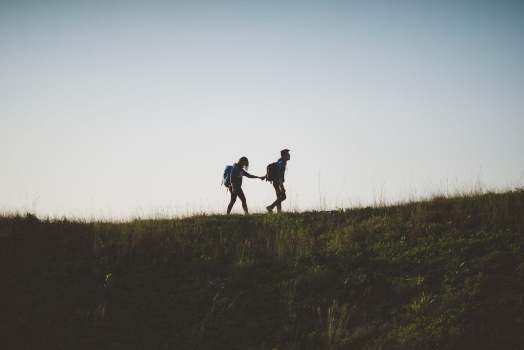 Building Trust couple walking on hill while holding during daytime