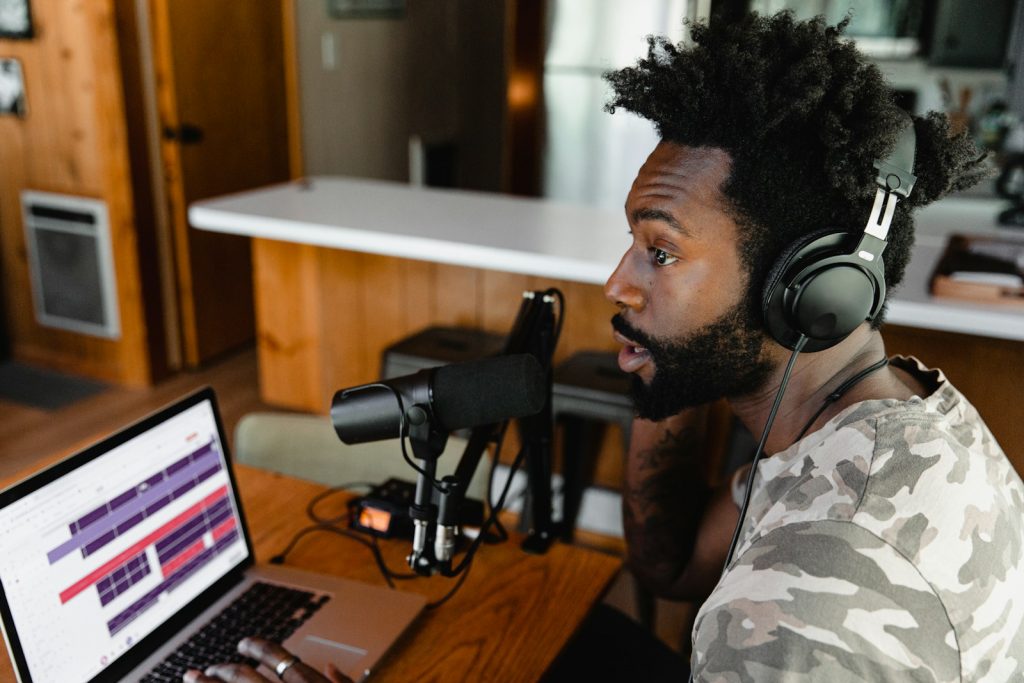 Naviguer dans l'Univers des Podcasts : Les 10 Meilleures Plateformes pour Écouter man in camouflage shirt sitting in front of laptop computer