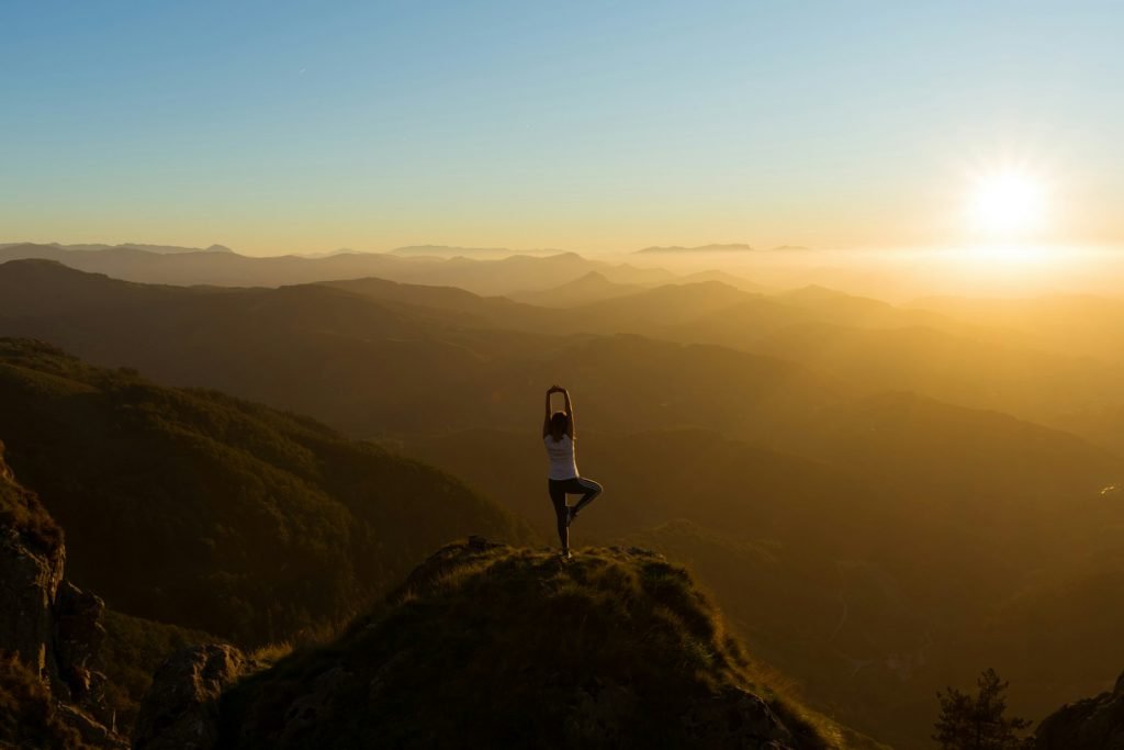 10 Sources de Sagesse : Nourrir le Chemin vers une Vie Épanouissante woman stretching on mountain top during sunrise