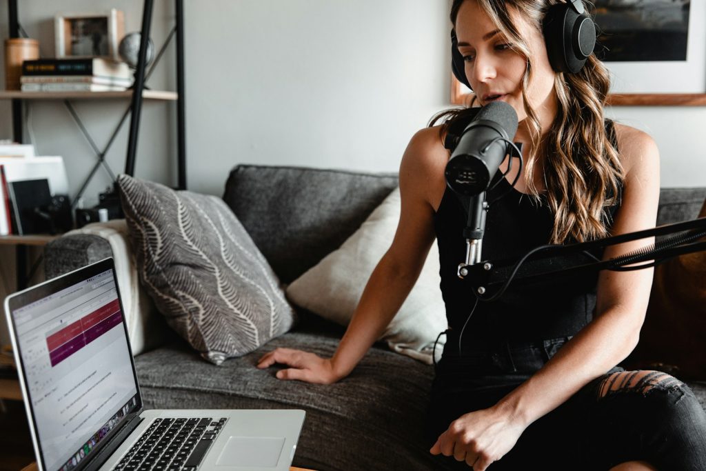 Naviguer dans l'Univers des Podcasts : Les 10 Meilleures Plateformes pour Écouter woman in black tank top sitting on couch using macbook