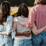 three women holding hand in front of flower garden