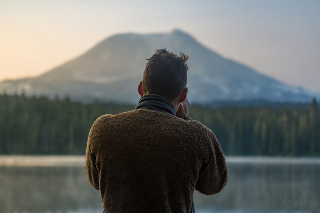 depth of field photography of man in gray sweater standing in front of mountain Capture the Golden Hours Mastering the Art of Travel Photography