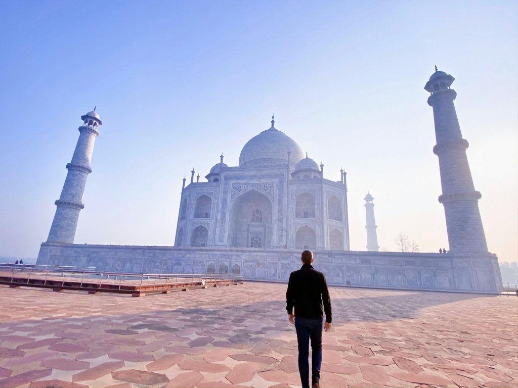 man in black jacket standing near mosque during daytime Taj Mahal.