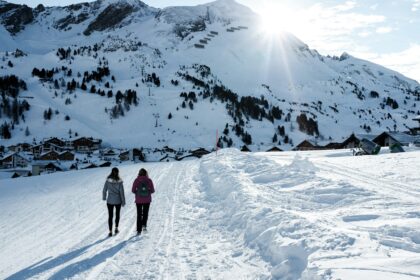 two person walking on snow covered ground during daytime