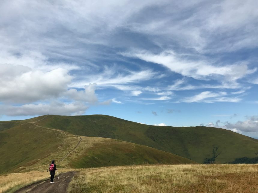 a person walking down a dirt road in the mountains