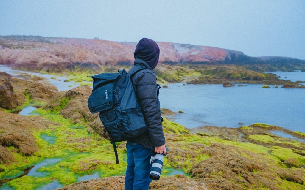 a man with a backpack is standing on a hill Rise of Digital Nomadism The Modern Wanderer
