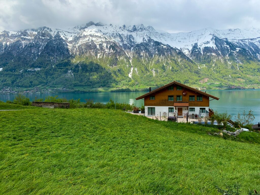 white and brown house near green grass field and mountain during daytime Interlaken Swiss Adventure
