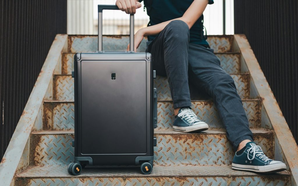 a person sitting on a set of stairs with a suitcase Choose Eco-Friendly Luggage Sustainable Packing