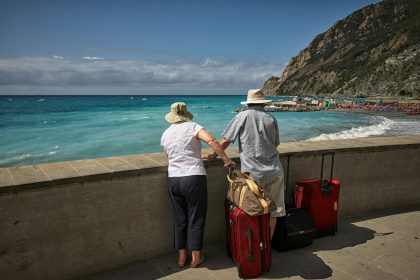 man and woman standing beside concrete seawall looking at beach