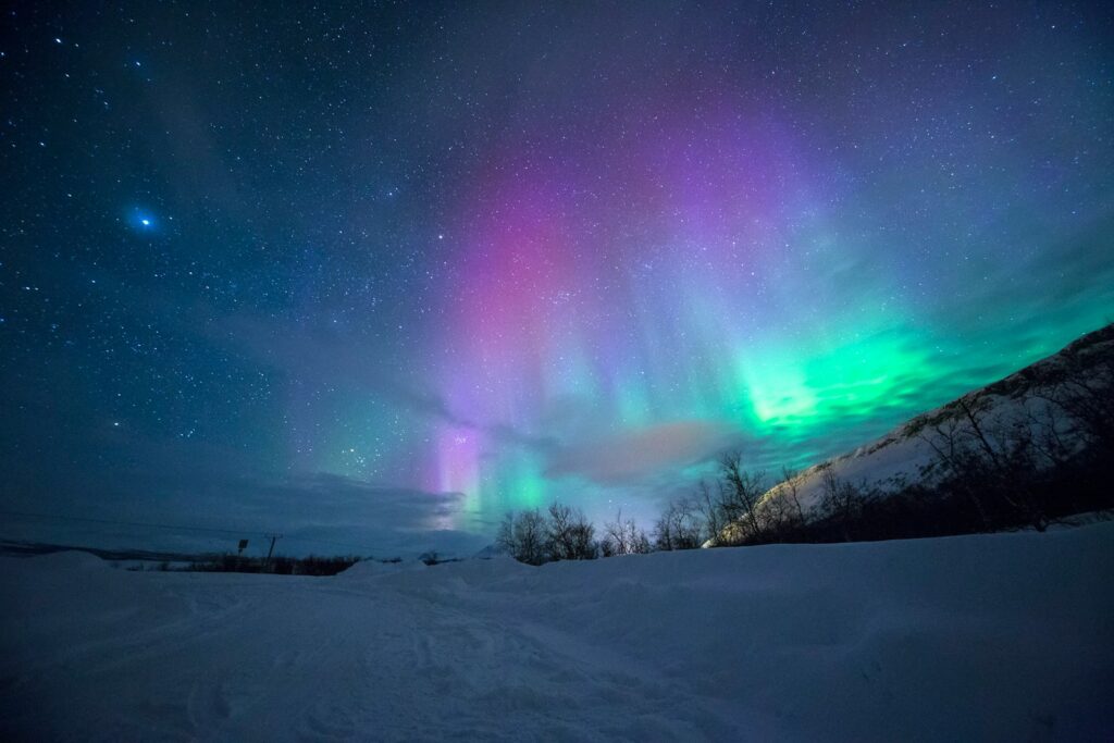 northern lights over snow-capped mountian Tromsø Norwegian Odyssey