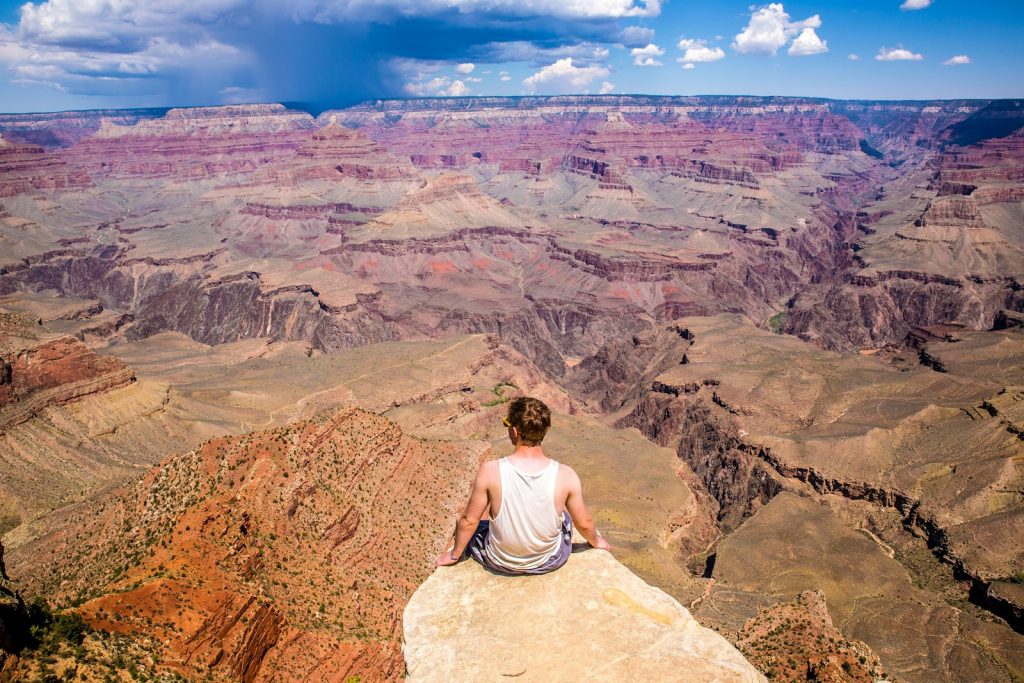 person sitting on cliff during daytime The Grand Canyon National Park Discovering Nature's Majesty