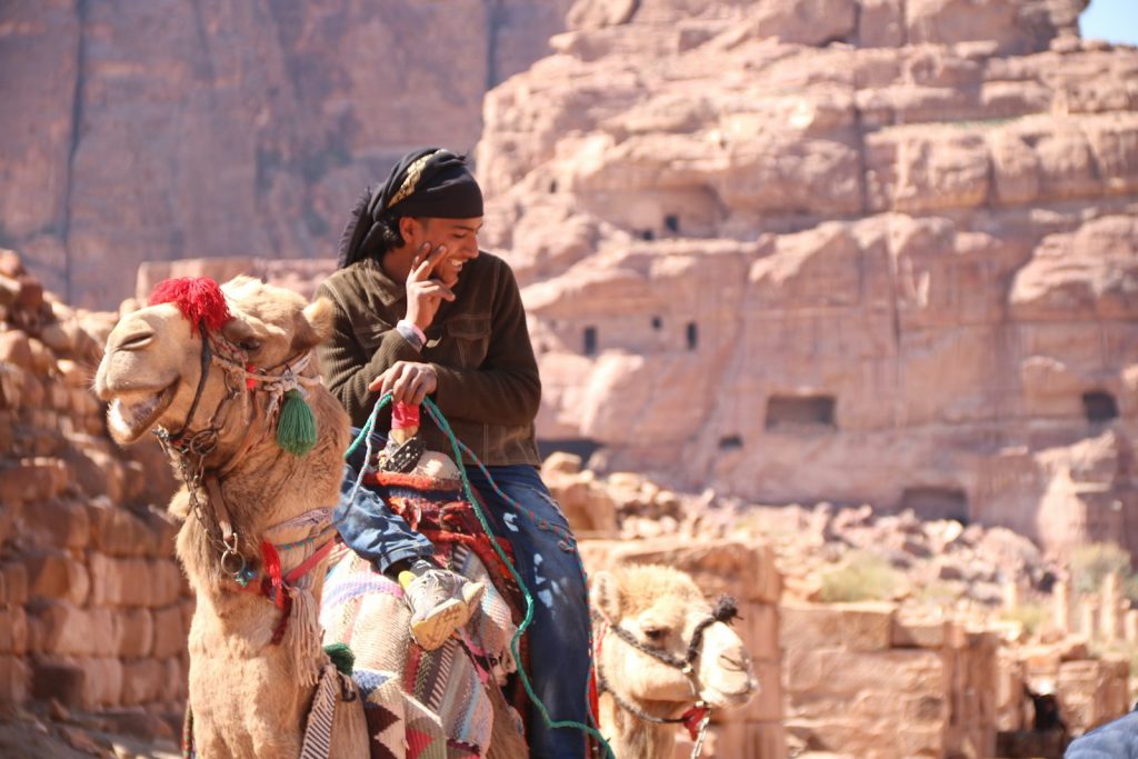 man in black helmet riding camel during daytime Petra Unveiling the Mysteries
