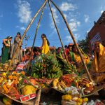 a group of people standing around a pile of fruit