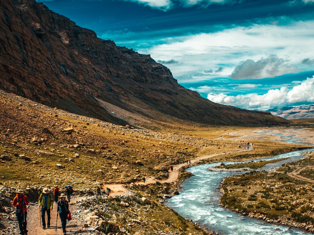 people walking on brown field near brown mountain under blue sky during daytime Pilgrimage Religious and Spiritual Pilgrimages