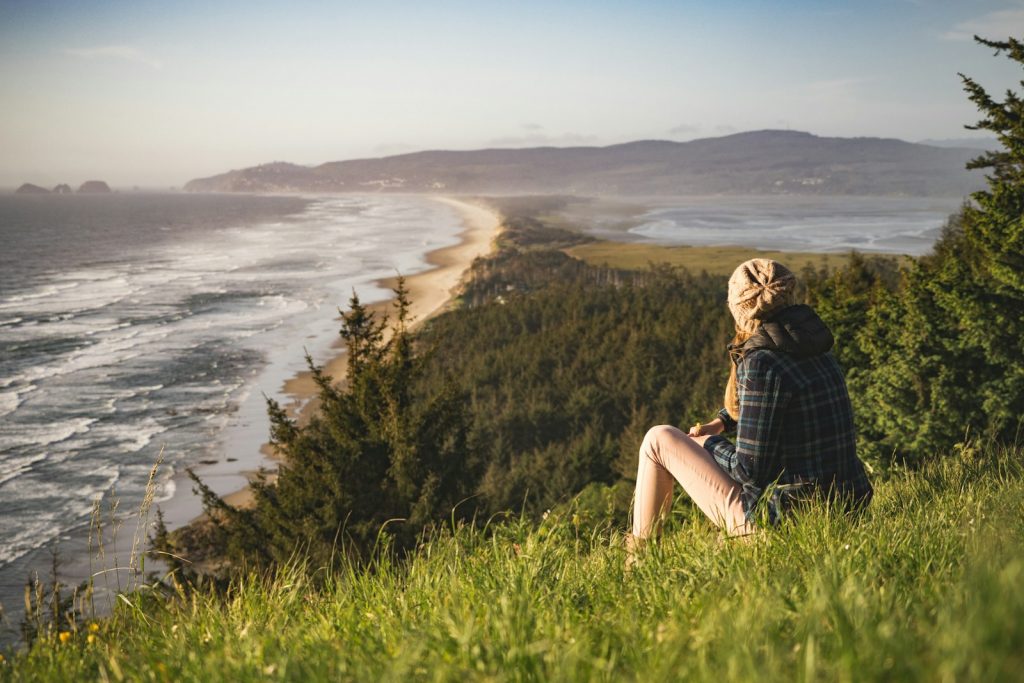 person sitting on hill near ocean during daytime Solo Travel