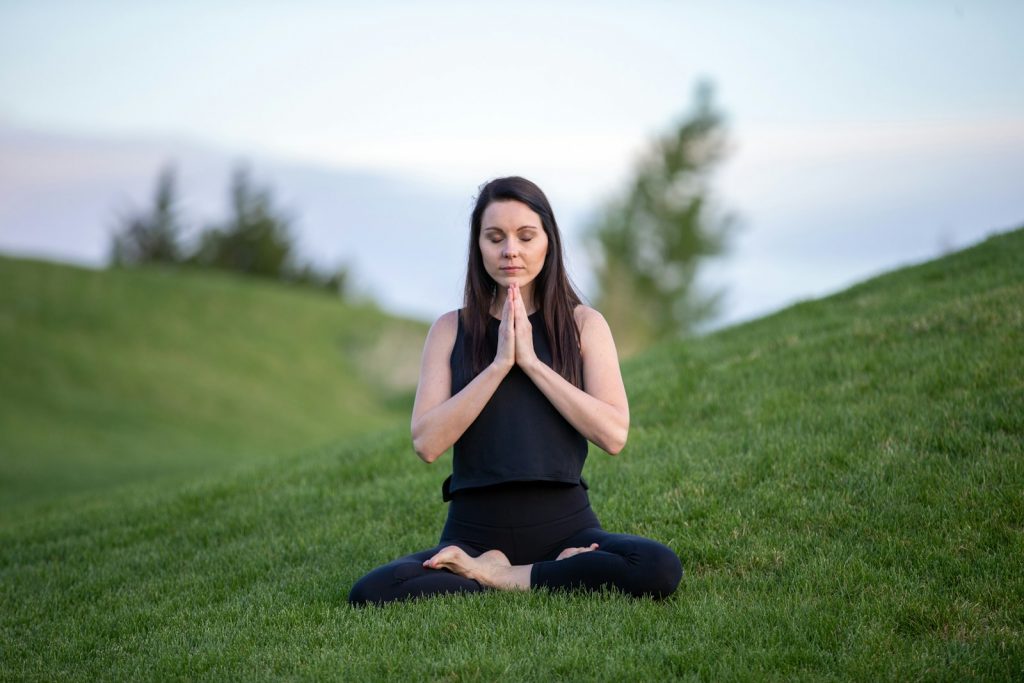 woman in black tank top and black pants sitting on green grass field during daytime Practice mindful packing Sustainable Packing