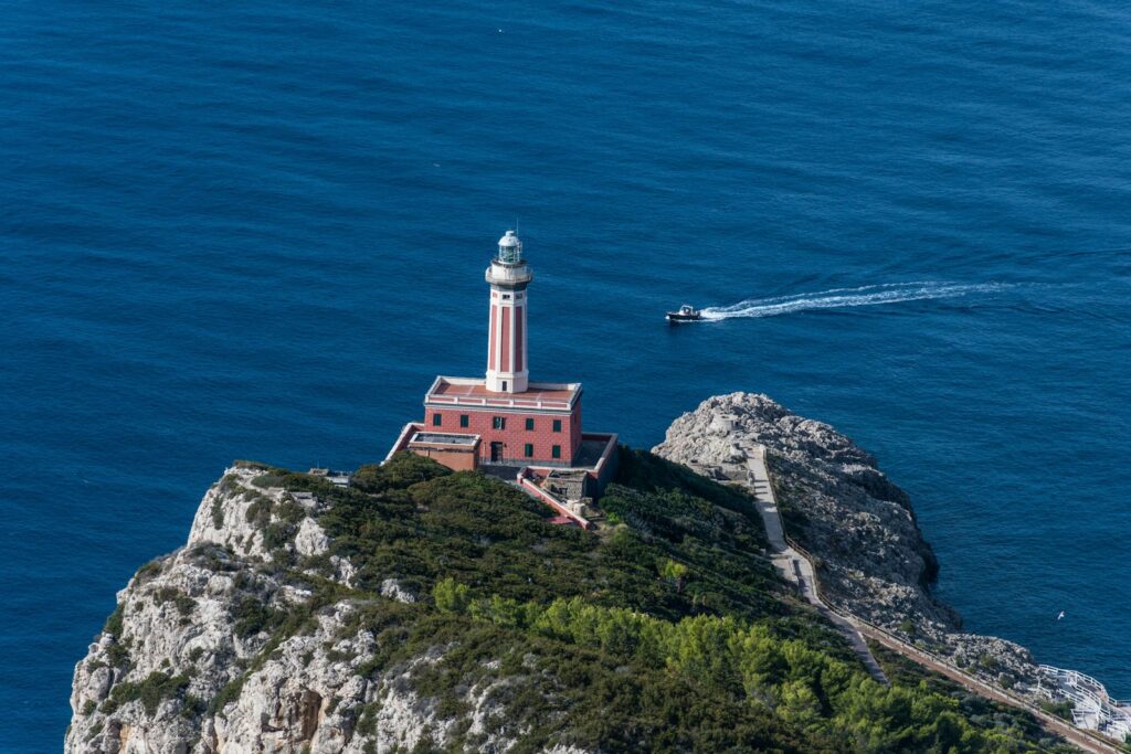 a lighthouse on a small island in the middle of the ocean Faro di Punta Carena World of Lighthouses