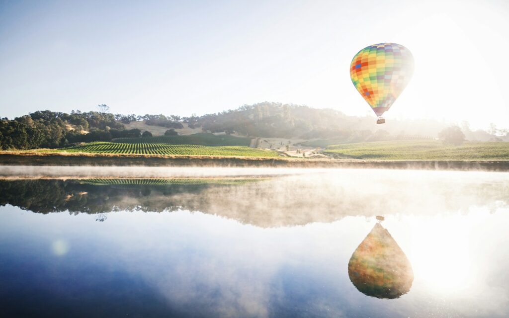 hot air balloon floating in mid air above body of water Napa Valley World of Wine