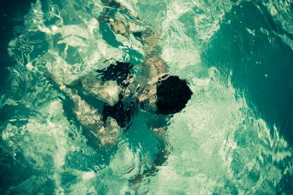 man swimming in green body of water