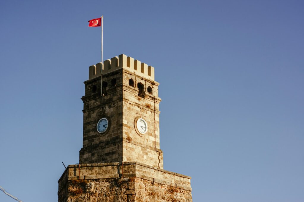 a clock tower with a flag on top of it Allure of Antalya