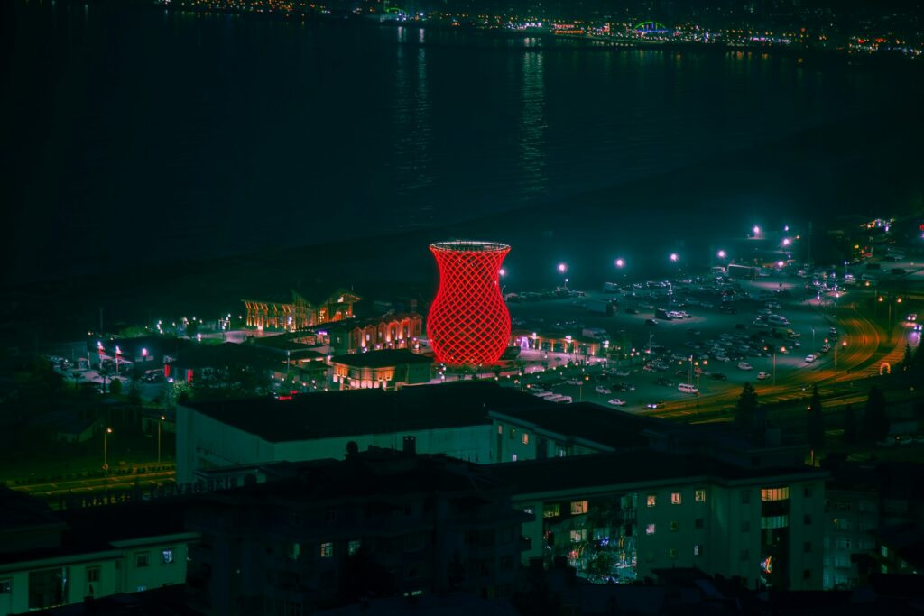 a tall red tower sitting on top of a lush green hillside