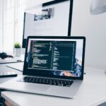 A MacBook with lines of code on its screen on a busy desk Amazon Web Services