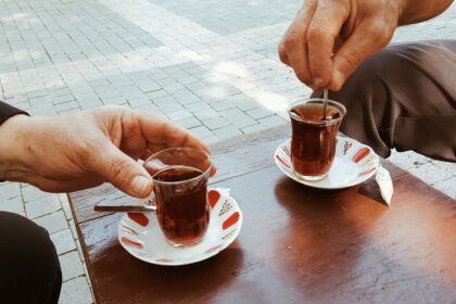 person holding clear glass mug with brown liquid