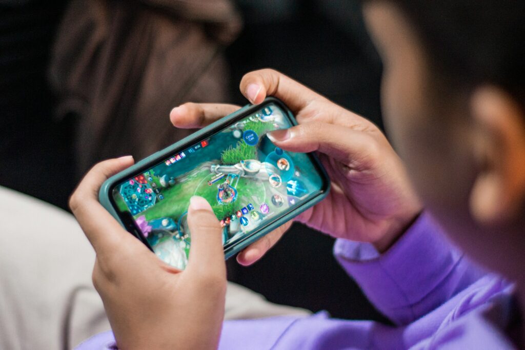 a person holding a cell phone in their hands Mobile Gaming World of Mobile Gaming
