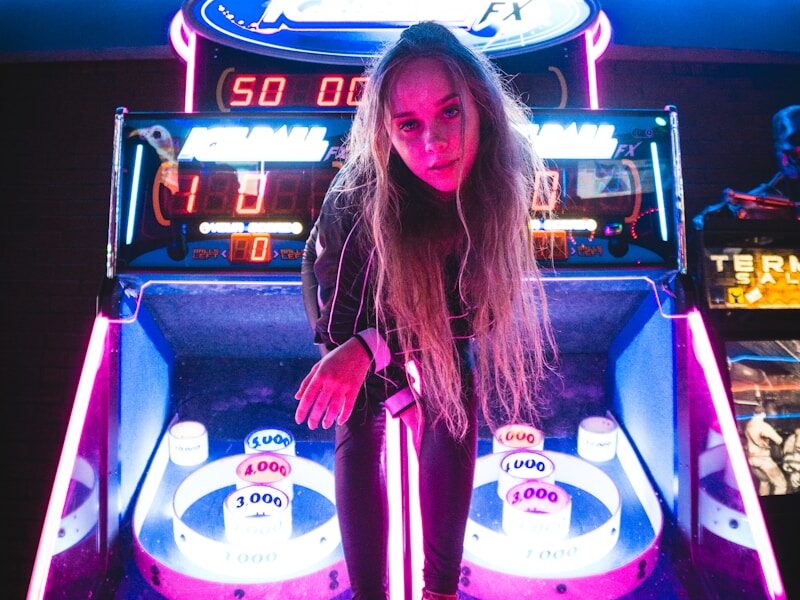 woman sitting on black and purple arcade game machine Fashion Games Egirlgames