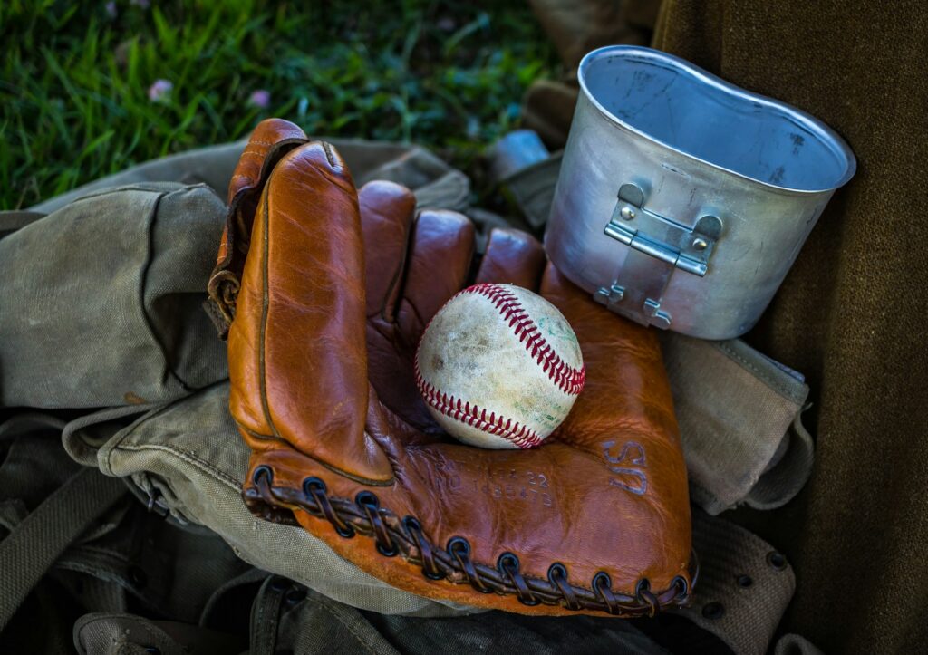 brown leather baseball mitt with baseball beside gray container and brown textile at daytime WWII Games Warfare 1944