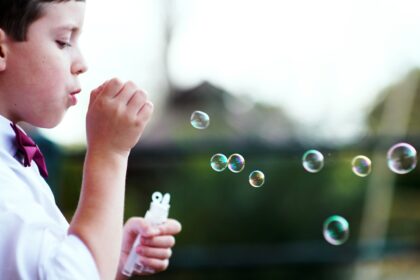 selective photography of boy playing with bubbles