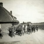 grayscale photo of men standing beside houses